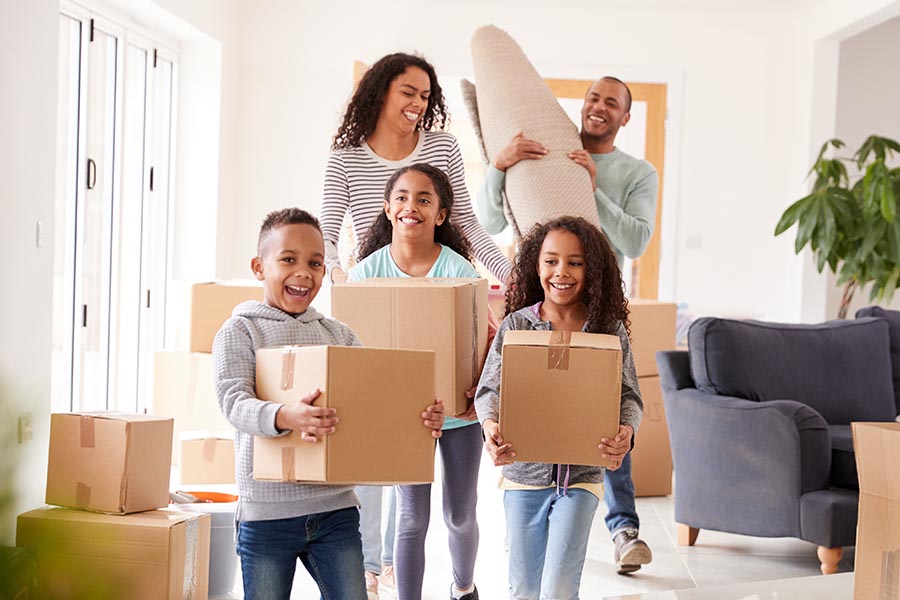 Personal Insurance - Family Moves in to Their New Home, Kids Carrying Boxes and Running Ahead, Everyone Smiling