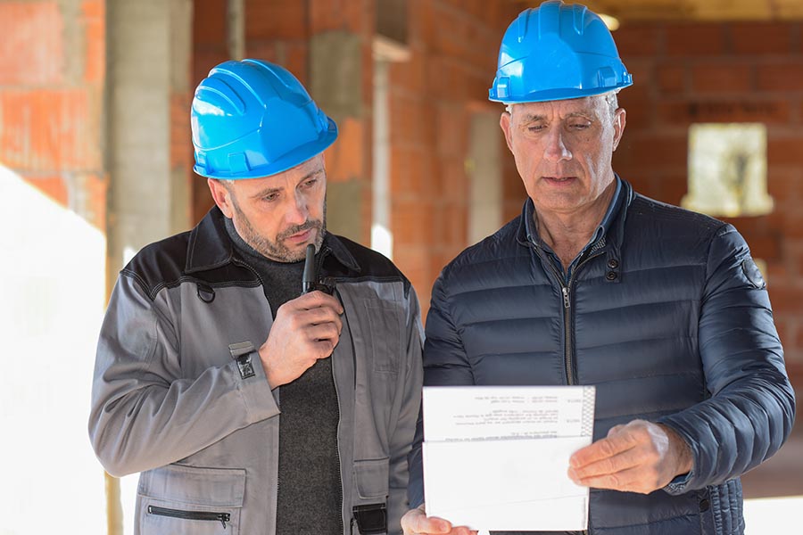 Specialized Business Insurance - Two Contractors Consulting on a Job, Wearing Blue Hardhats